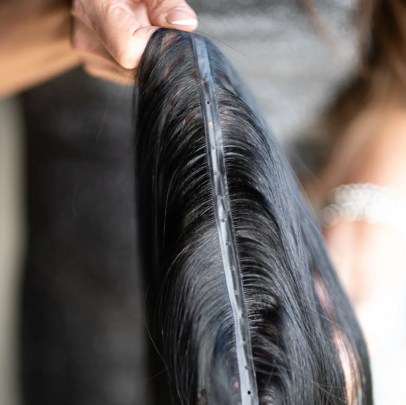 Hand holding a no-sew hair extension weft
